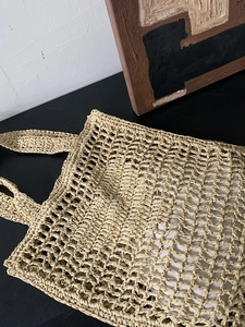 Vue détaillée d'un sac cabas en paille tressée beige avec motif ajouré en maille
