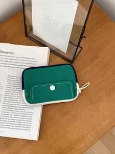 Detailed top view of a dark green canvas mini pouch on a cozy wooden desk with books