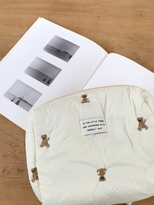 Detailed view of white quilted storage bag with bear embroidery and chic fabric label