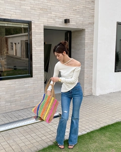 Detailed view of a handmade rainbow striped straw tote bag with rope handles