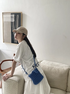 Detail of blue hand-woven crochet mini crossbody bag with hollow knit texture and strap