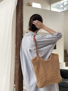 Handmade woven straw tote bag with brown leather straps for a minimalist summer style