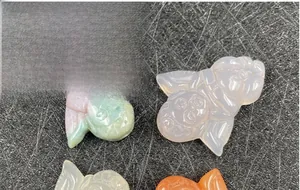 Detailed view of colorful carved agate angel pendants in green pink and white