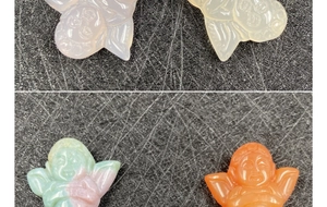 Macro detail of four hand-carved agate angel pendants in diverse natural colors