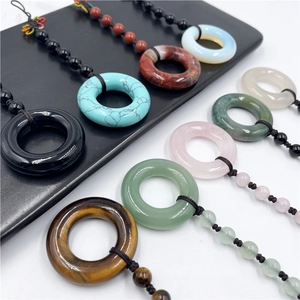 Various natural gemstone donut pendants including rose quartz and tiger eye with woven cords