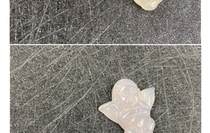 Macro detail of hand-carved agate angel pendant with wings and translucent finish