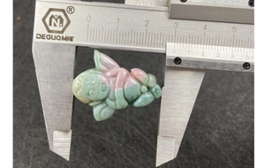 Macro view of carving pendant measured with calipers showing 25mm width on agate