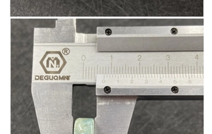 Close-up view of measuring a 7mm polished light blue agate angel pendant with a caliper