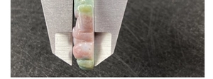 Measuring the thickness of a delicate two-tone agate angel pendant with a metal caliper