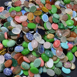 Vista macro di vari cabochon ovali in pietre preziose tra cui occhio di tigre e quarzo