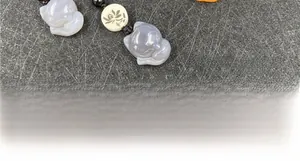 Dettaglio macro di ciondoli volpe in agata intagliata con perla loto su cordino intrecciato