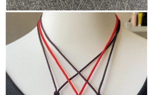 Dettaglio della collana a doppio cordone intrecciato rosso e marrone su un manichino