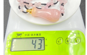 Dettaglio di una collana con boccetta di profumo in quarzo rosa dal peso di 43g