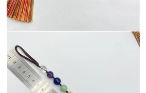 Détail du pendentif en pierres chakra avec pompons et mesure à la règle