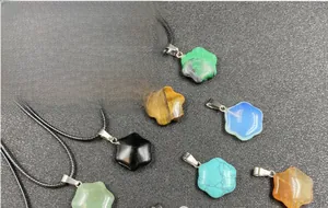 Close-up of hexagonal star and flower stone pendants with woven cords on black background