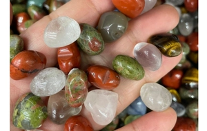 Detailed view of hand holding various polished natural tumbled stone crystals and gems