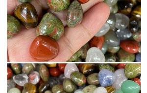 Macro shot of assorted polished natural crystal tumbled stones in palm for size scale