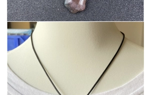 Detail of reddish-brown natural gemstone necklace shown on a model with black cord