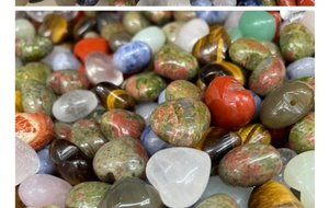 Macro shot of assorted heart-shaped and tumbled gemstones including rose quartz and tiger eye