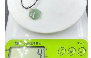Detailed weight measurement showing light green star pendant on a digital scale