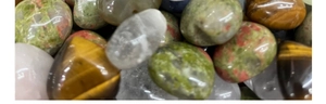 Close-up of polished rose quartz, tiger eye, and clear quartz heart-shaped stones