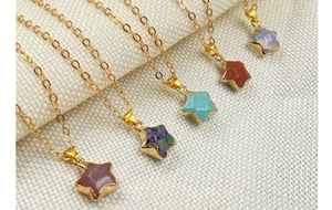 Close-up of gold star pendants featuring assorted natural gemstones on a textured fabric