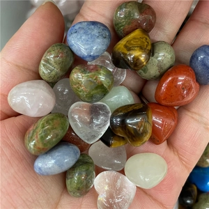 Handheld assorted polished crystal hearts and oval stones in natural semi-precious minerals