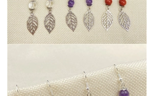 Macro detail of handmade silver leaf drop earrings with crystal beads on linen background