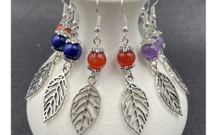 Detail of silver drop earrings featuring colorful stone beads and hollow leaf pendants
