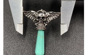 Detail view of gothic winged skull pendant with turquoise stone measured by caliper