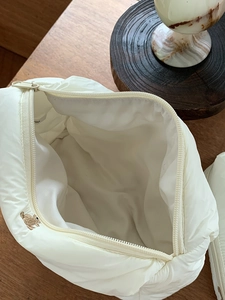 Quilted beige cosmetic bag with bear embroidery shown from a top-down interior view
