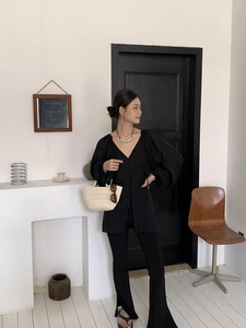 Chic black V-neck long sleeve top with flared slit pants and woven straw beach handbag