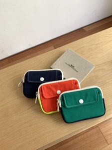 Overhead view of three colorful canvas coin purses and mini storage pouches on wooden desk