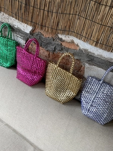 Detail of four colorful metallic woven tote bags in green, purple, gold, and light blue