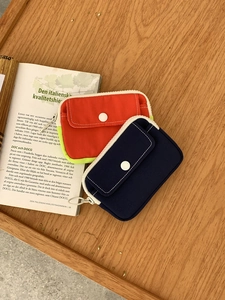 Close-up of canvas mini coin purses with front pockets on a wooden tray and book