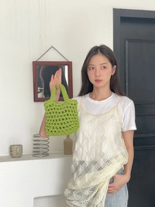 Detailed close-up of grass green hand-woven mini tote bag with hollow crochet texture