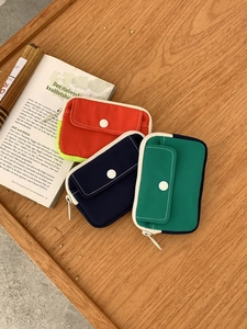 Three colorful canvas coin purses with snap pockets arranged on a wooden surface