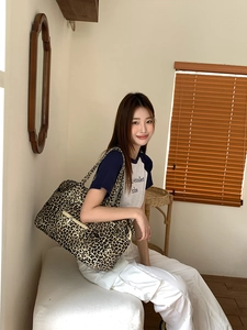 Detail shot of leopard print canvas tote bag with front zipper pocket and shoulder strap