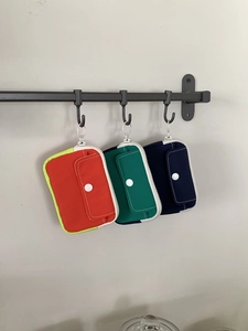Close-up of canvas mini coin purses in three colors hanging on a metal rack hooks
