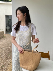 Detail of woven straw tote bag paired with a white crochet dress for a summer resort style