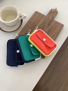 Detailed view of colorful canvas mini pouches for coins and earphones on a wooden tray