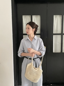 Close-up of a handmade beige crochet mesh tote bag styled with a casual summer dress