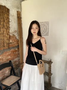 Detail of a handmade straw crossbody bag paired with a summer knit top and maxi skirt