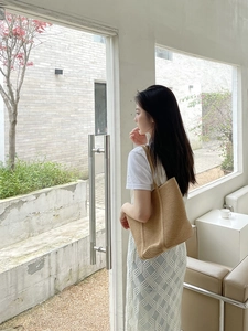 Lifestyle shot of a khaki knit tote bag with vertical stripes shown on a model