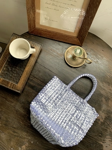 Top view of purple woven tote bag with square texture on vintage dark wood desk