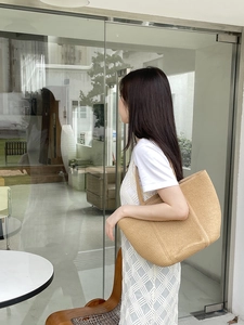 Outdoor lifestyle shot of a large straw woven tote bag with flat shoulder straps