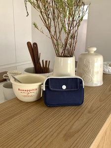 Mini navy canvas pouch for coins and earphones on a wooden table with rustic decor