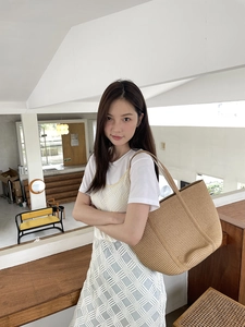 Detailed view of natural straw woven tote bag with vertical stripes shown on a model