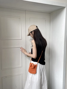 Detail of hand-woven crochet crossbody bag in bright orange with cotton rope texture