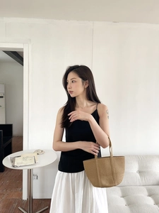 Close-up of minimalist straw tote bag styled with white skirt for summer leisure